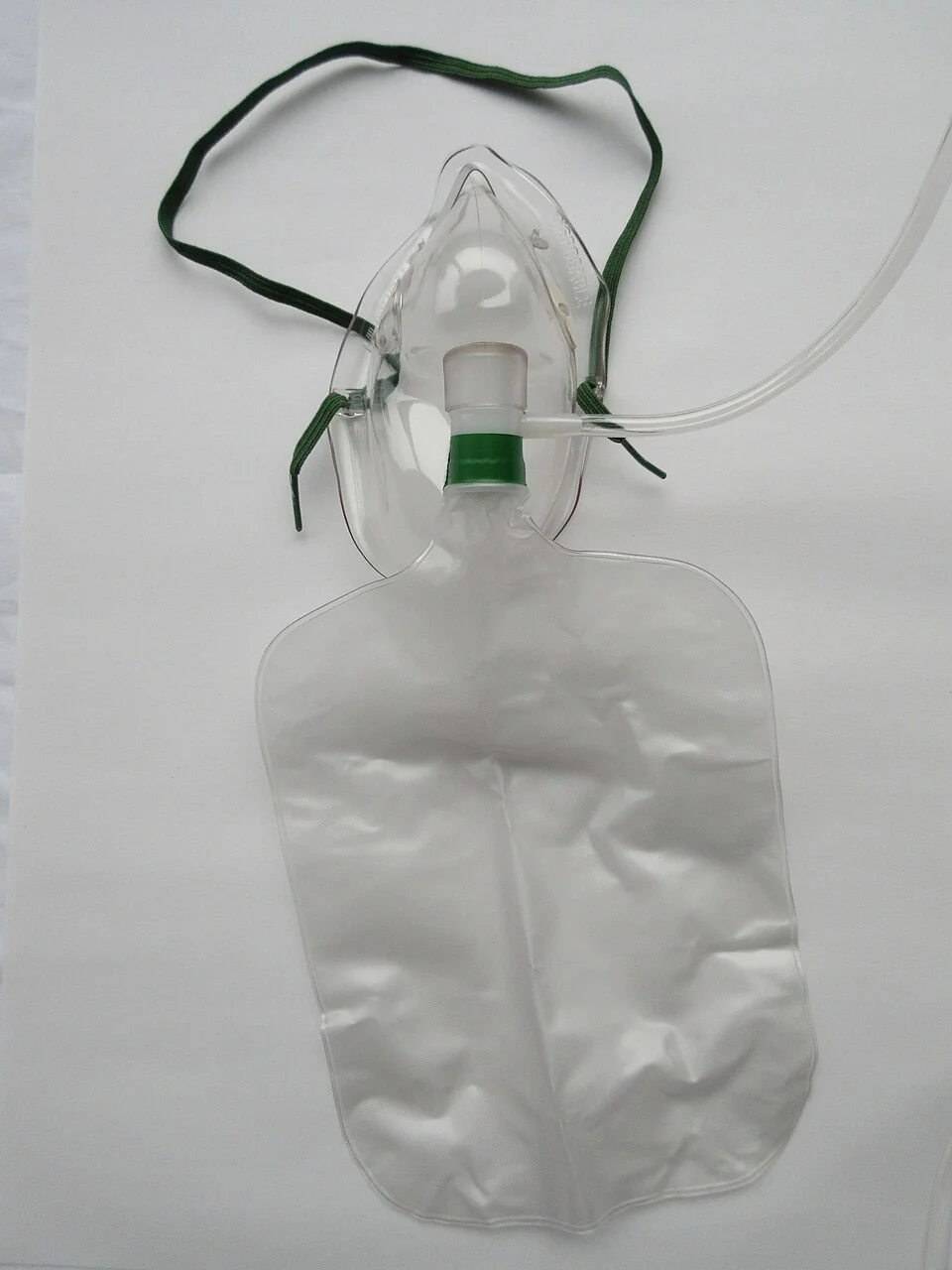 A clear plastic non-rebreathe oxygen mask with an elastic head strap, a one-way valve at the mask inlet and a large transparent reservoir bag attached below, connected to oxygen tubing.